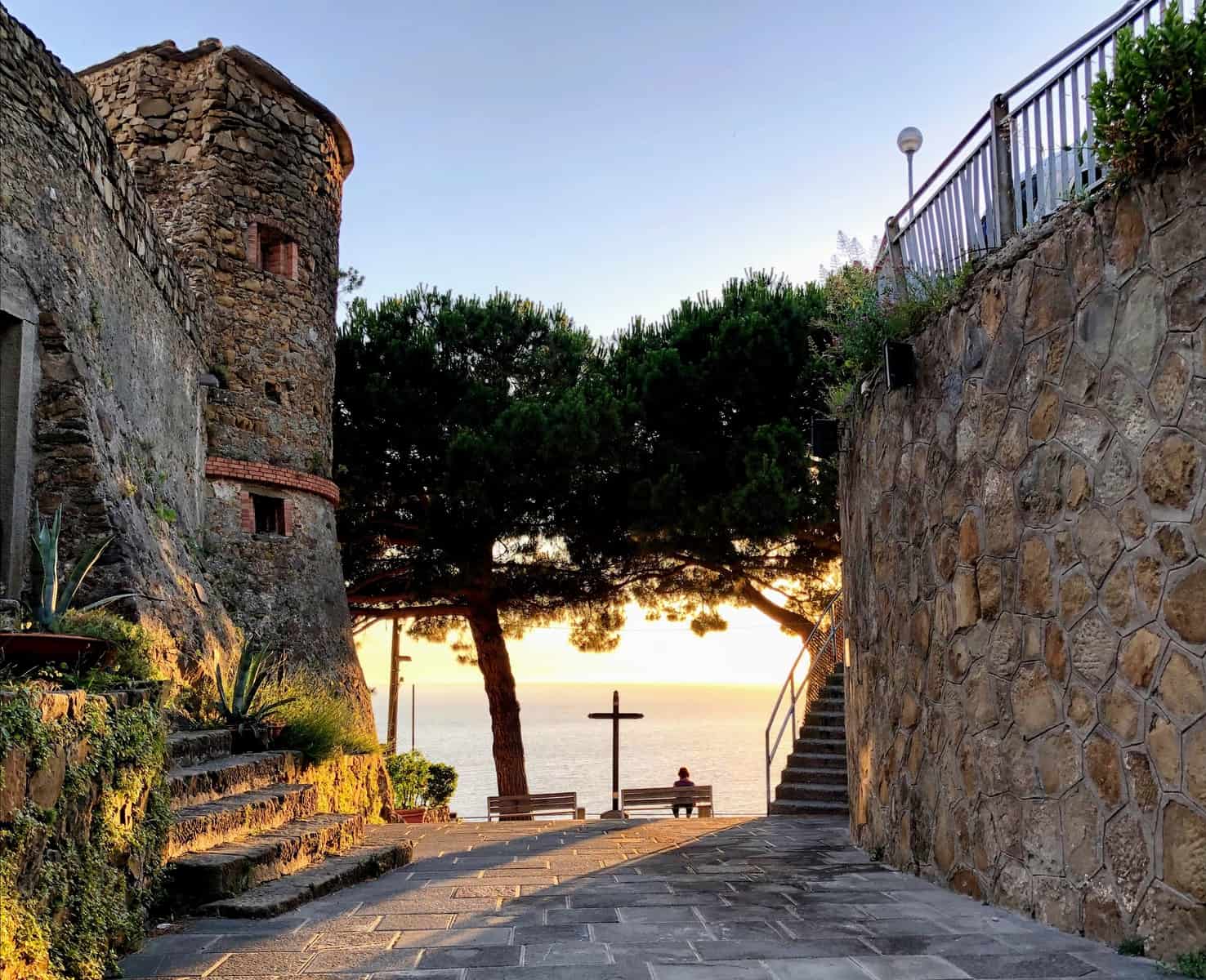 Cinque Terre Riomaggiore Castle Silhouette Person Sitting On Bench Sunset Pine Trees Cross Stone Wall Mediterranean Sea