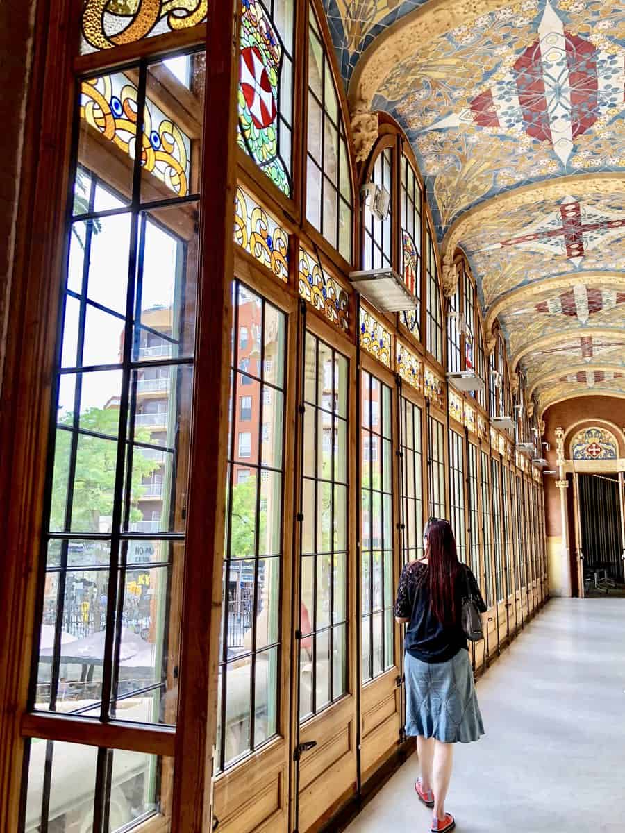 Hospital Of The Holy Cross Woman Walking Along Wall Of Stained Glass Windows