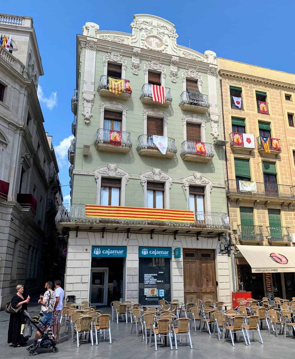 Reus Spain Casa Pinol Pastel Art Nouveau Building Exterior With Catalan Flag And Cafe Chairs And Three Pedestrians