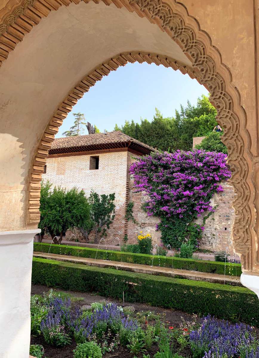 Alhambra Generalife Garden View From Archway Purple Flowers With Hedge And Water Spouting