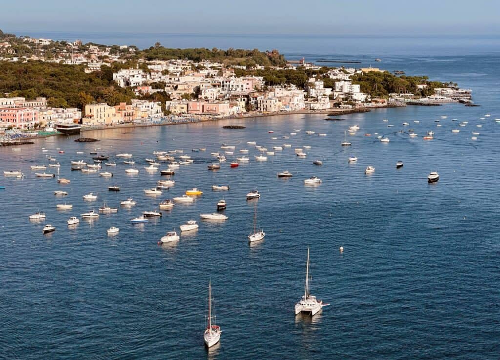 Ischia Ponte Italy Island Boats On Calm Sea Morning Light Pastel Houses Line Shoreline