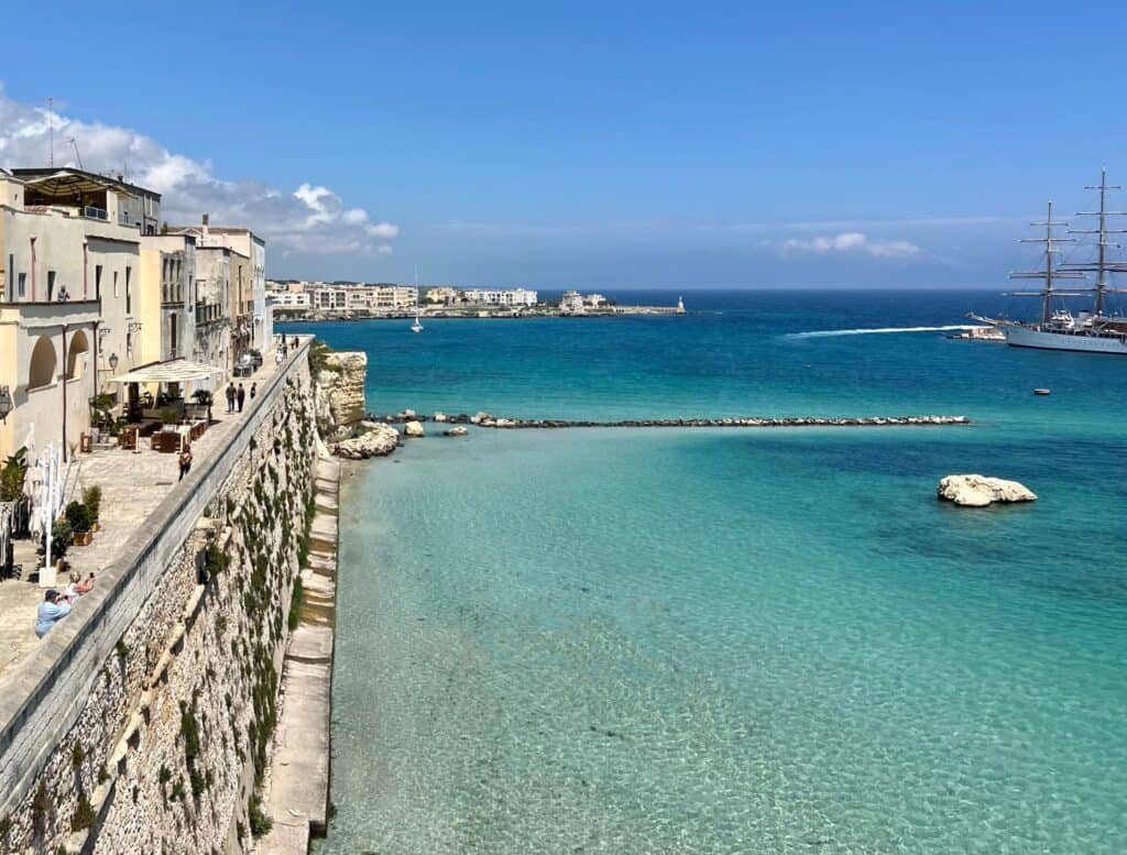 Otranto Puglia Clear Turquoise Sea And Town Wall With Buildings And Promenade