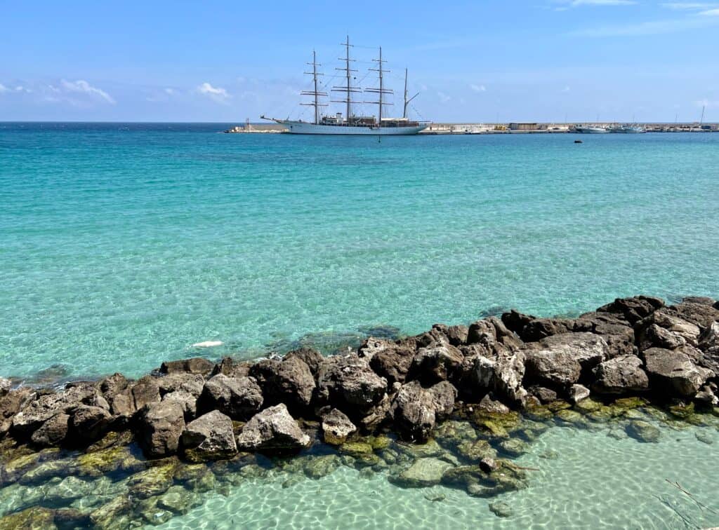 Otranto Salento Puglia Adriatic Sea Clear Turquoise Water With Rocks And Large Sailboat