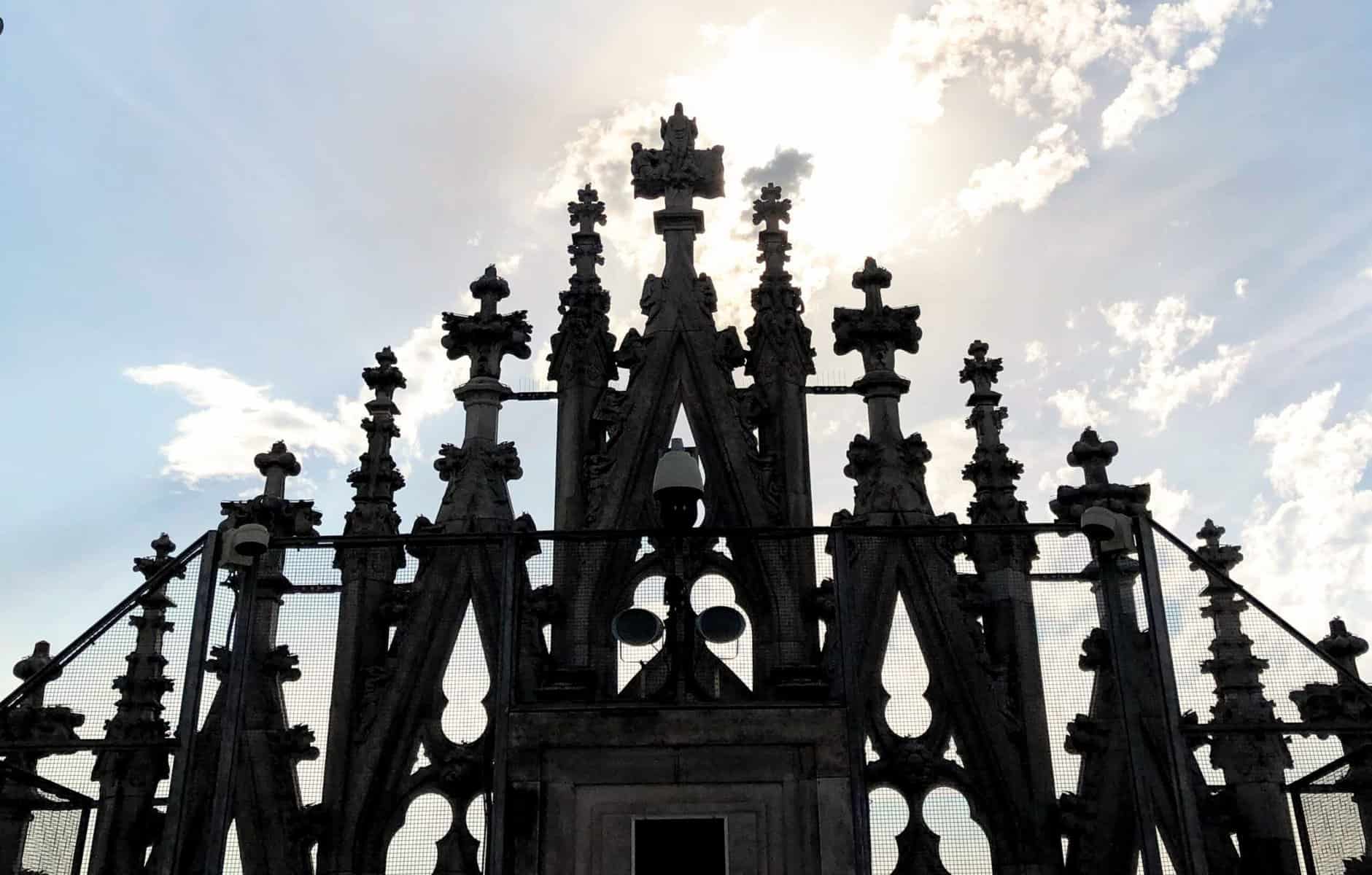 Milan Duomo Roof Top Front Gothic Facade With Spires And Cross With Sunlight And Clouds