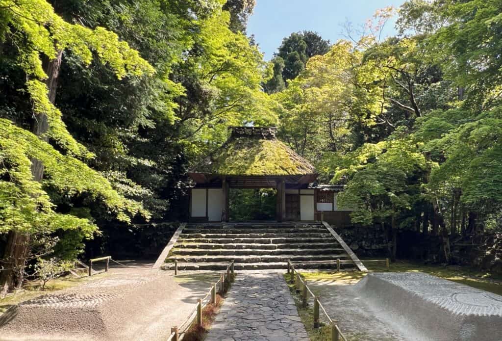 Honen-in Temple Gate With Mossy Thatched Roof Framed By Trees And Two Mounds Of Sand With Traced Designs Kyoto Japan